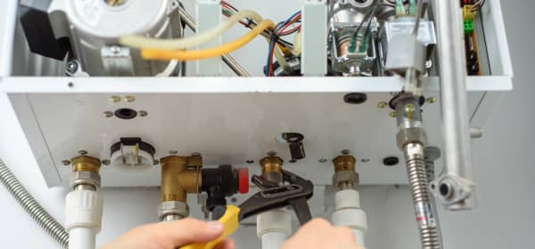 Nahansicht der Hände eines Monteurs, der an einer Gasheizung arbeitet