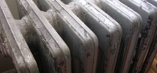 Alter Gliederheizkörper mit abgeplatzter Farbe in einem Wohnraum