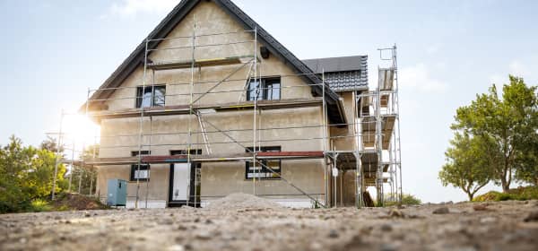 Haus mit Gerüst auf unbepflanztem Boden bei blauem Himmel