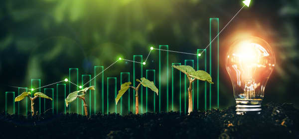 Leuchtende Glühbirne und junge Pflanzen in Erde neben ansteigendem Diagramm