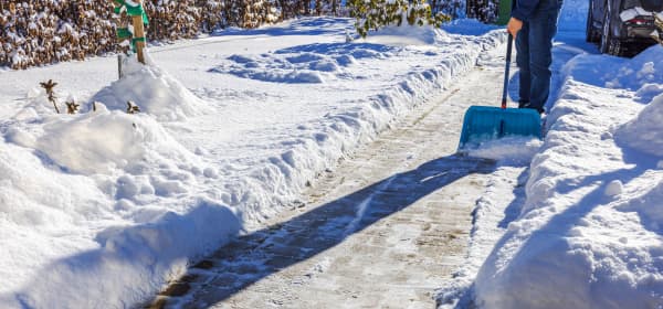 Verschneite Einfahrt, die von einer Person geräumt wird