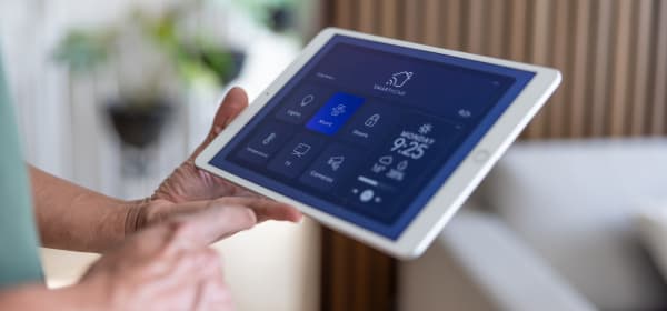 Ältere Person hält ein Tablet mit Smart-Home-Anwendung