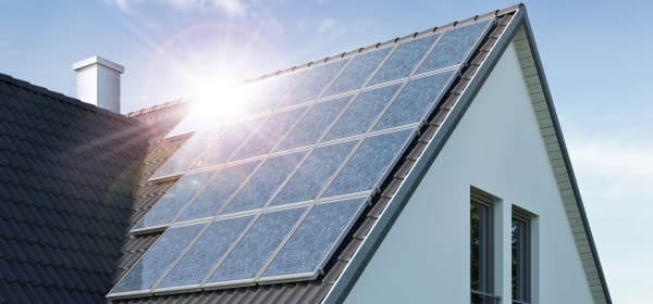 Sonne spiegelt sich in Solarmodulen auf dem Dach eines Wohnhauses