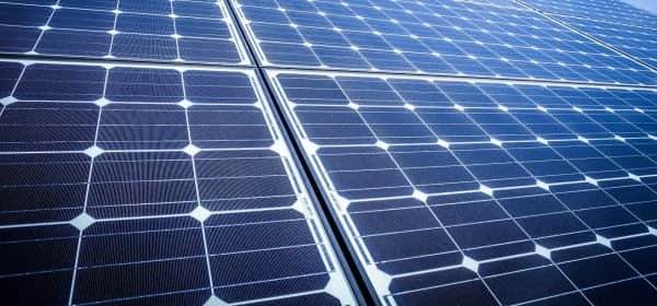 Nahaufnahme mehrerer Photovoltaikmodule auf einem Schrägdach bei blauem Himmel mit einigen Wolken