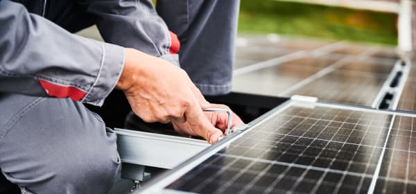 Nahaufnahme eines Arbeiters, der ein Solarmodul auf einem Dach installiert