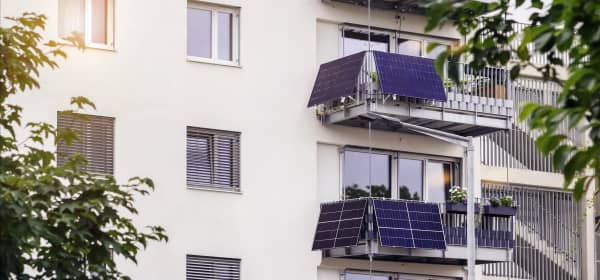 Ansicht der Fassade eines gepflegten Mehrfamilienhauses mit Balkonen, an denen sich Balkon-Solaranlagen befinden