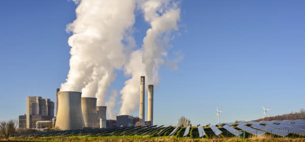 Kohlekraftwerk, Solar und Windräder vor blauem Himmel
