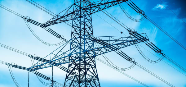 Einzelner Hochspannungsmast vor blauem Himmel