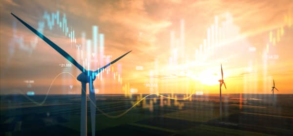 Windräder bei Sonnenuntergang, im Vordergrund Börsendiagramme