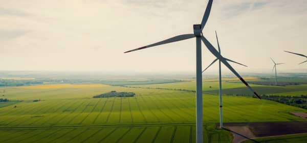 Windkraftanlagen auf grüner Wiese vor bewölktem Himmel