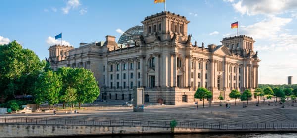 Seitenansicht des Reichstagsgebäudes in Berlin mit blauem, leicht bewölktem Himmel und Sonnenschein
