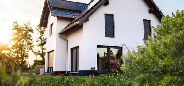 Außenansicht eines neu gebauten Einfamilienhauses in Deutschland. Das Haus ist mit Solarpanelen auf dem Dach ausgestattet und nach modernen Standards der Nachhaltigkeit gebaut.