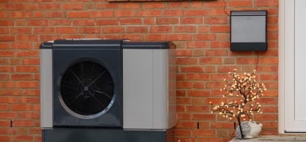 Wärmepumpe neben Eingang eines Altbaus aus rotem Backstein