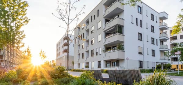 Grünanlage vor einem modernen Mehrfamilienhaus in Deutschland bei Sonnenuntergang