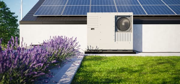 Eine auf dem Dach eines Einfamilienhauses installierte Wärmepumpe mit Photovoltaik-Paneelen zusammen mit einem begrünten Dach über der Garage