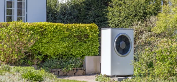 Wärmepumpe im Garten vor einem Haus im Grünen