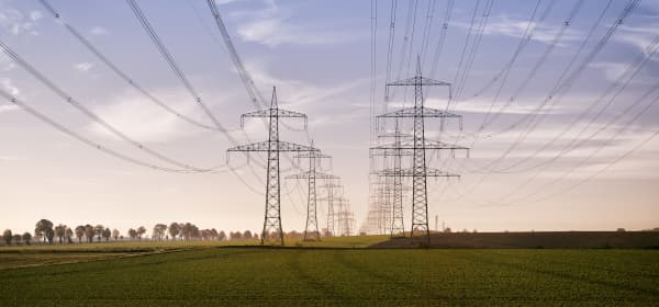 Strommasten in zwei Reihen bei Sonnenaufgang