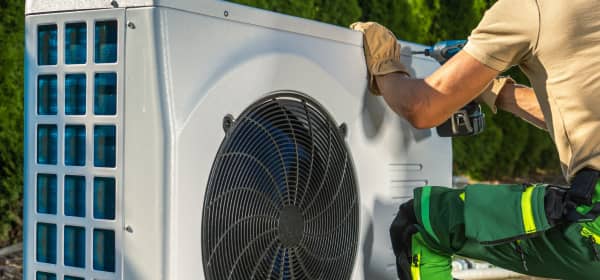 Handwerker arbeitet an einer Wärmepumpe im Freien
