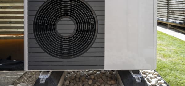 Luft-Wärmepumpe im Garten vor Holzwand zum Lärmschutz