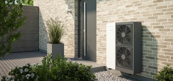 Grau-weiße Wärmepumpe neben der Haustür eines modernen Wohnhauses