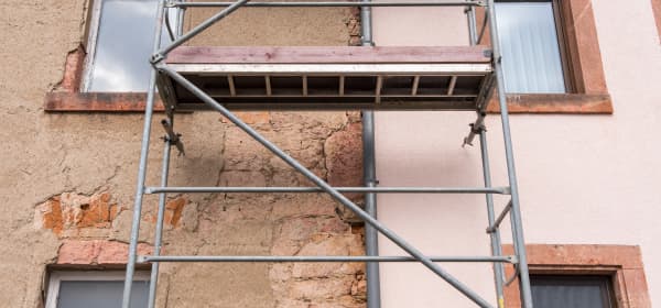 Bestandsimmobilie mit Gerüst; eine Hälfte ist saniert, eine Hälfte unsaniert