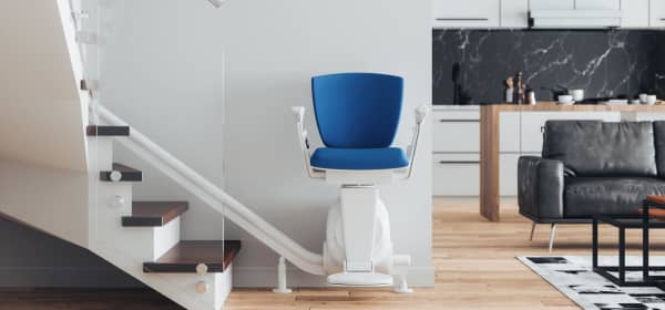 Sitzlift mit blauem Polster am Fußt einer Treppe in einem modernen Eigenheim