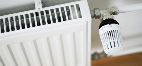 Schrägansicht von oben auf einen weißen Heizkörper. Das Thermostat ist auf Stufe 4.