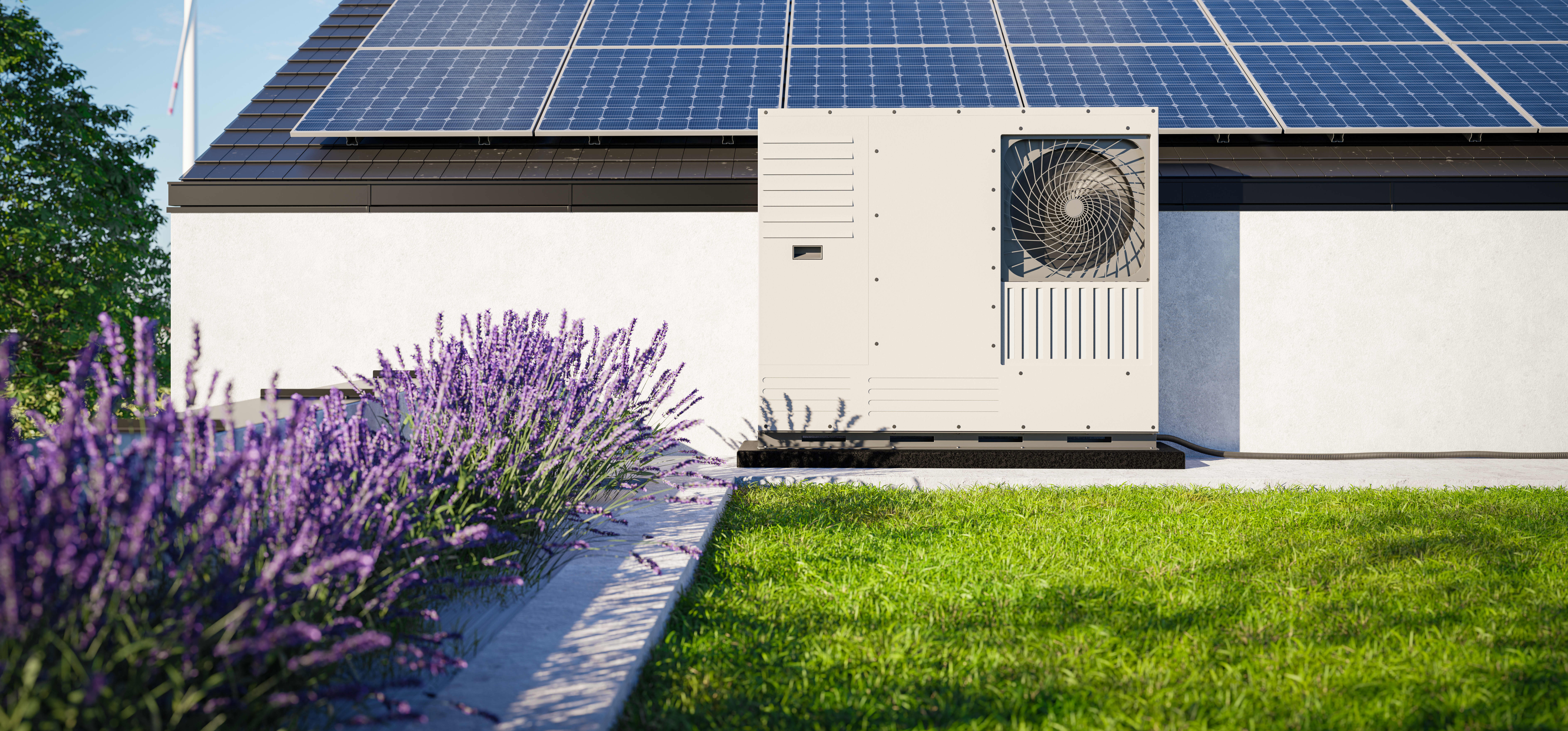 Wärmepumpe vor Haus mit Solaranlage auf dem Dach vor einem Lavendelbeet und grünem Rasen. Im Hintergrund steht ein Windrad