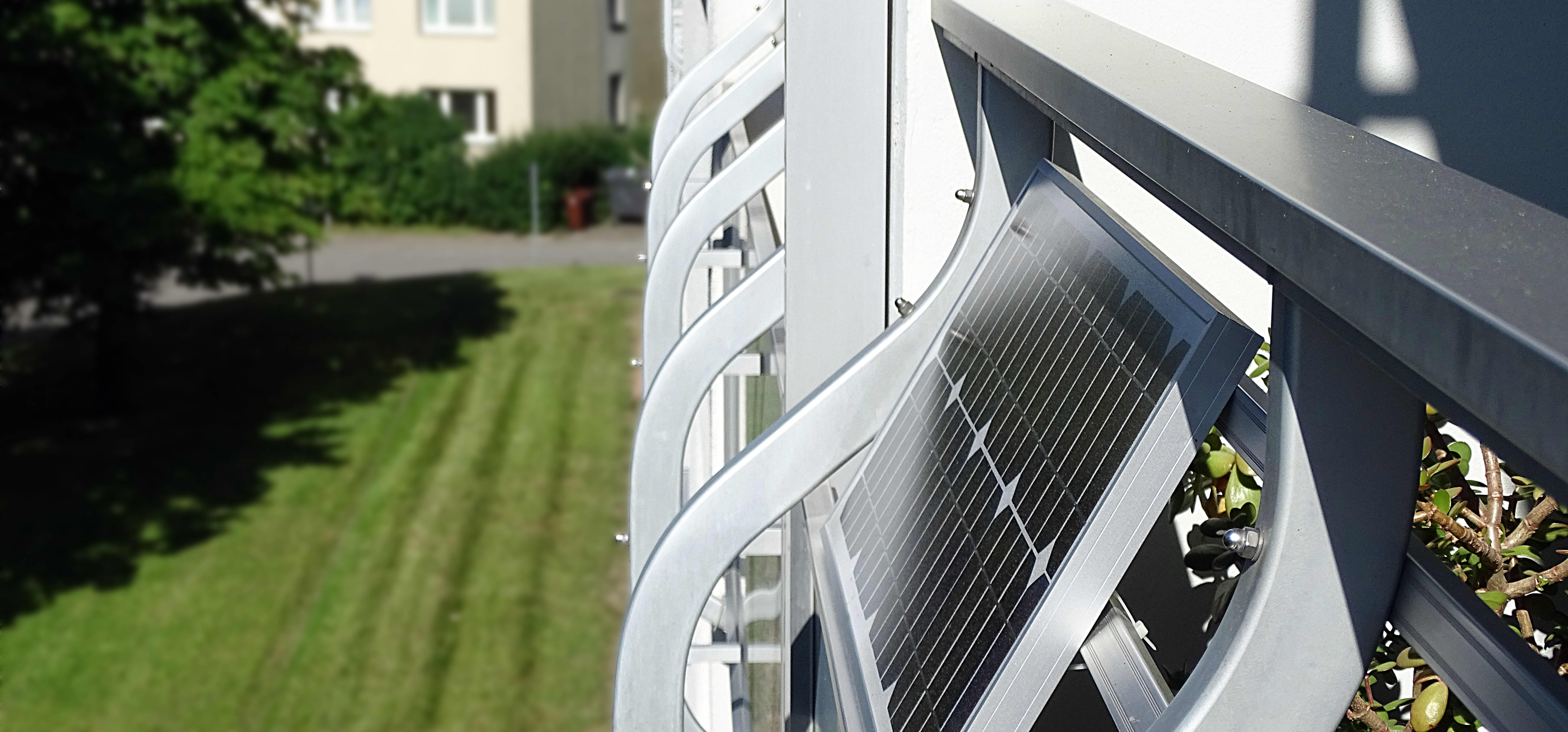 Seitenansicht eines Mehrfamilienhauses mit Balkonen, der Fokus liegt auf einem Solarmodul, das an einem der Balkone montiert ist