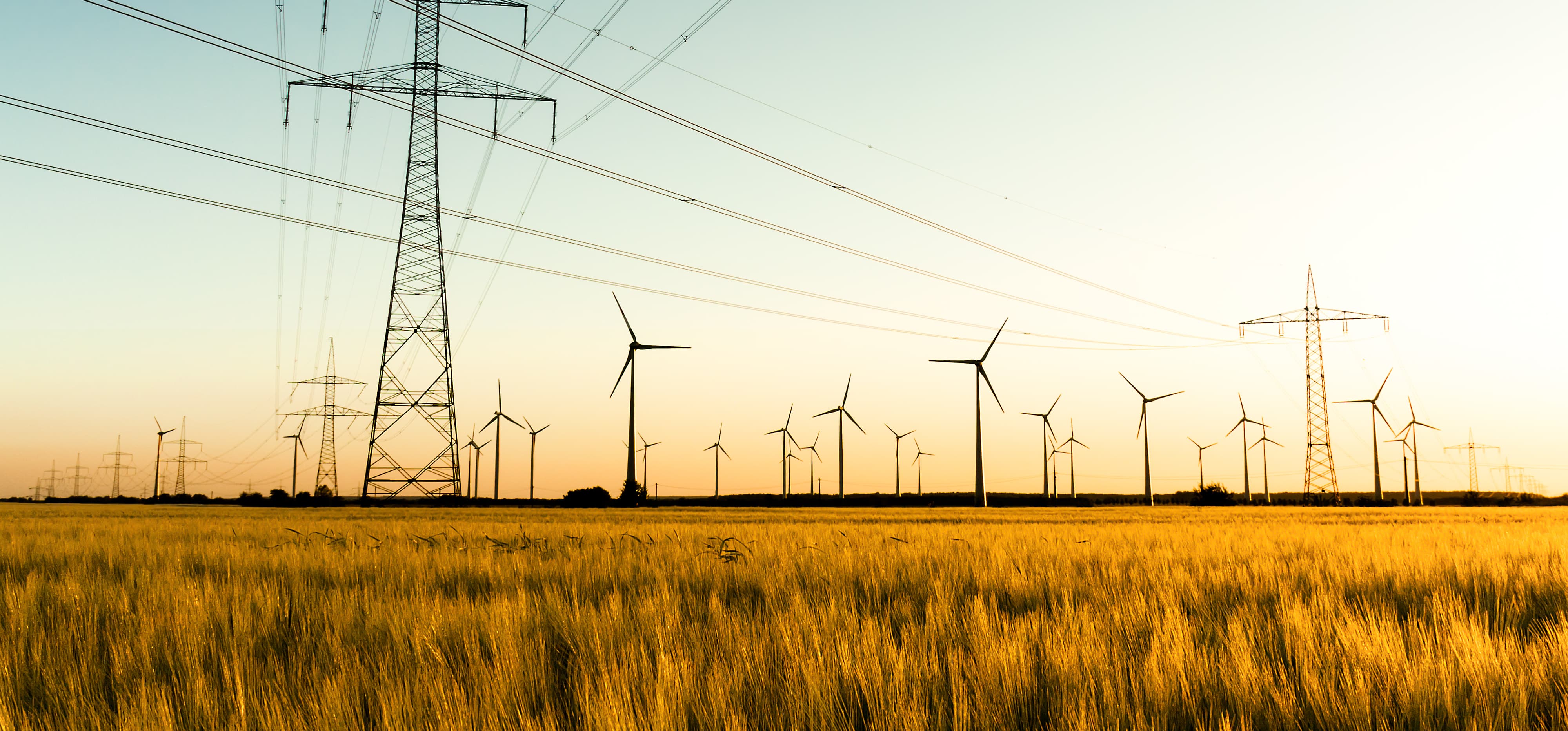 Strommasten und Windräder bei Sonnenuntergang