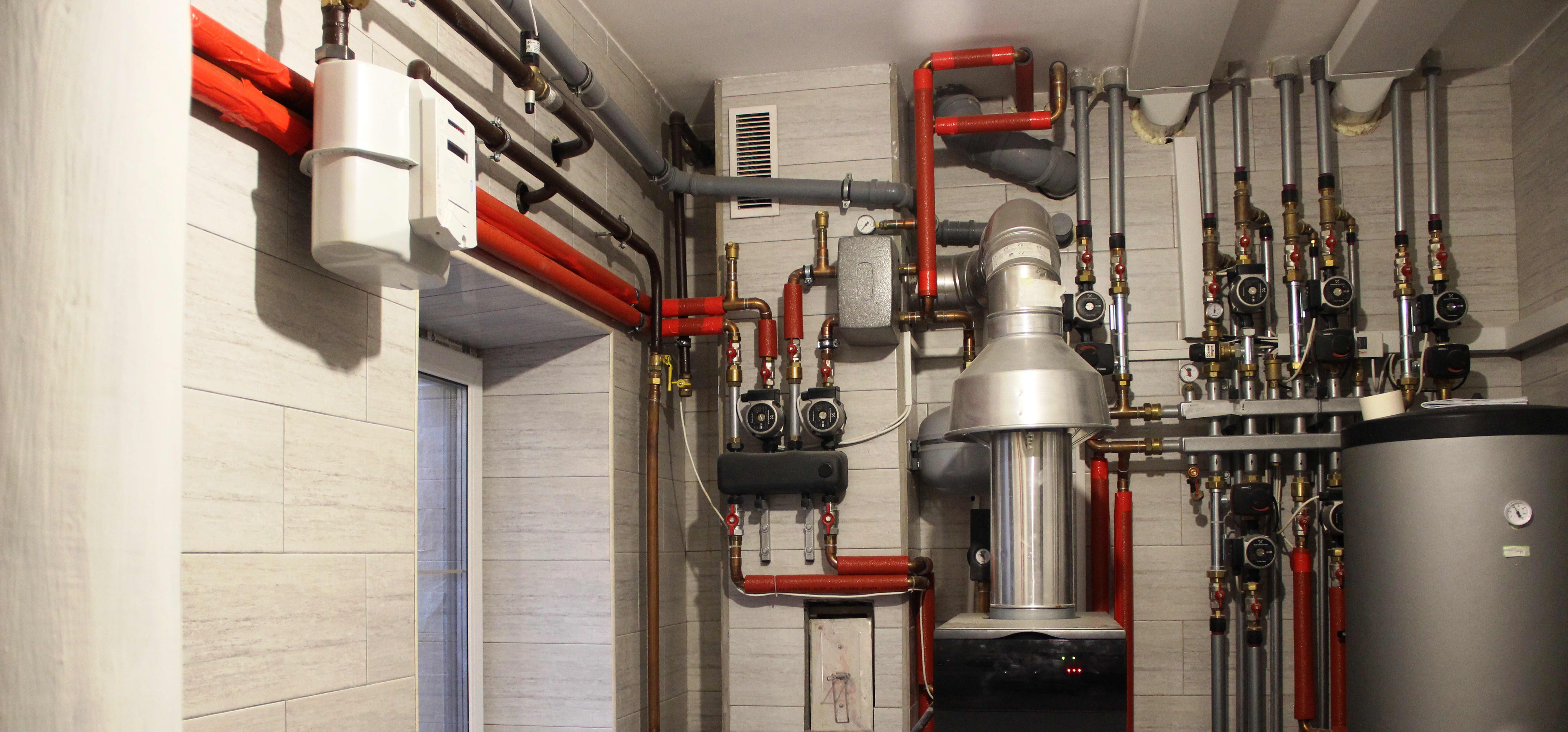 Heizungssystem im Kesselraum mit Kessel, Warmwasserbereiter, Expansionstank und Rohren