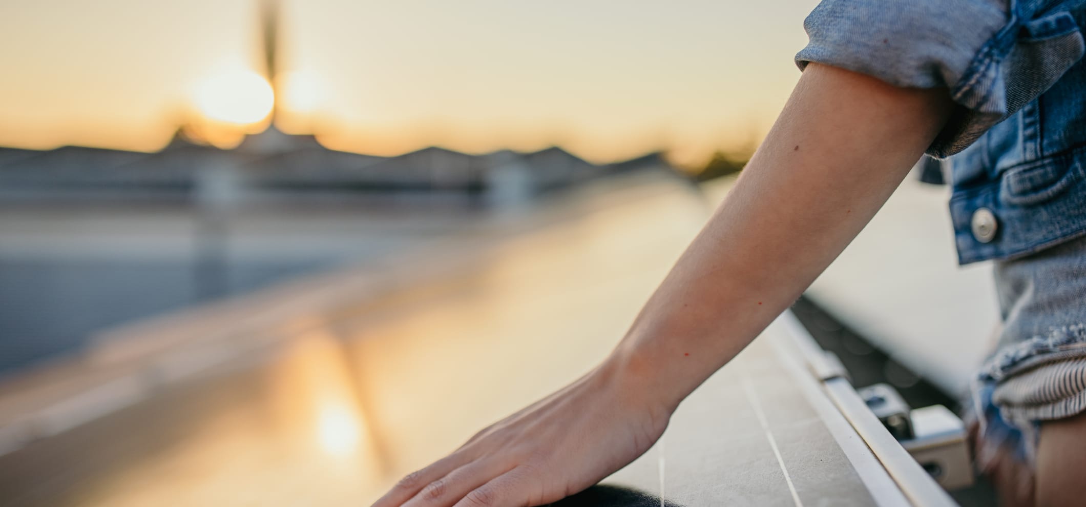 Hand berührt Solarpanel vor Sonnenuntergang