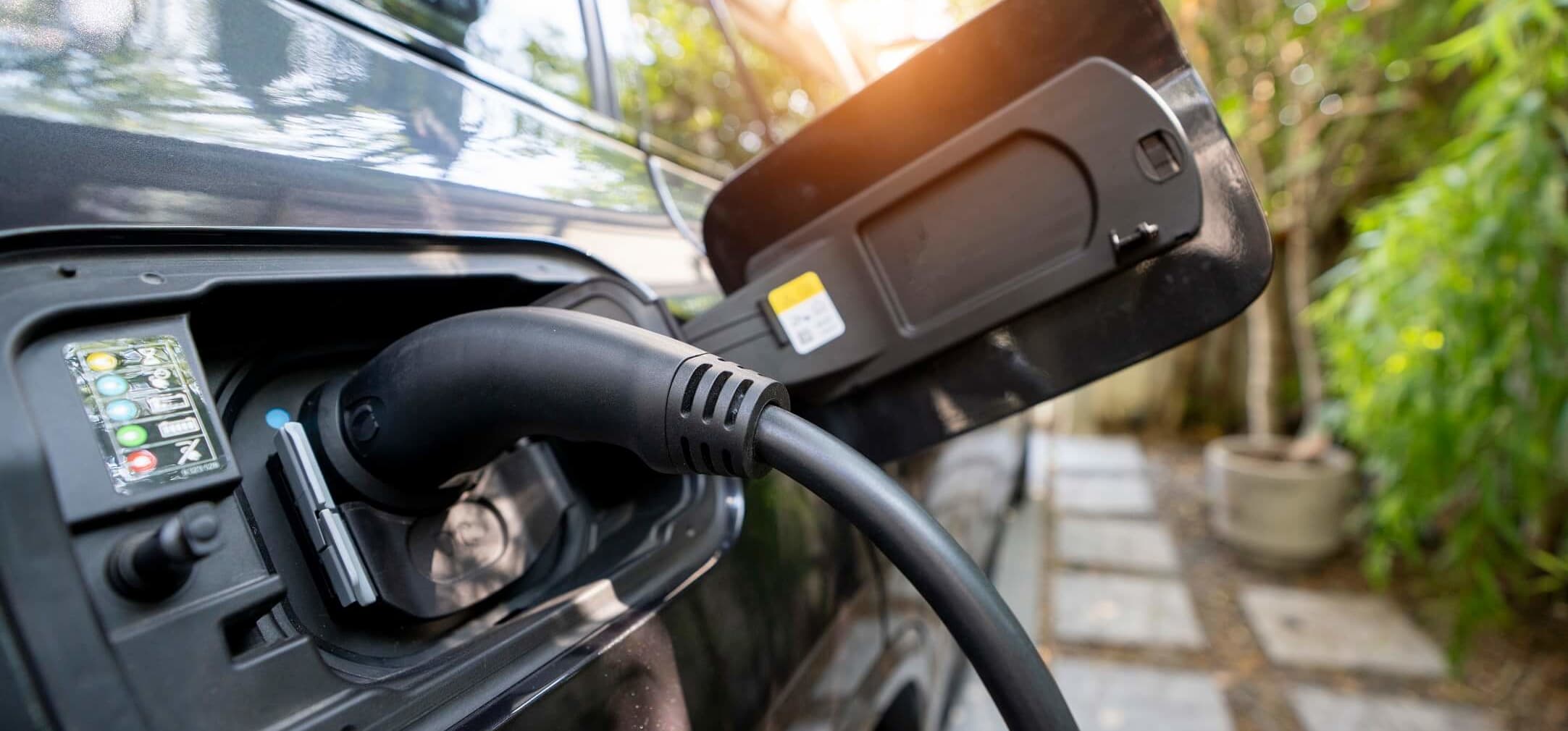 Nahaufnahme eines Elektroautos, das auf dem eigenen Grundstück an einer privaten Ladestation geladen wird