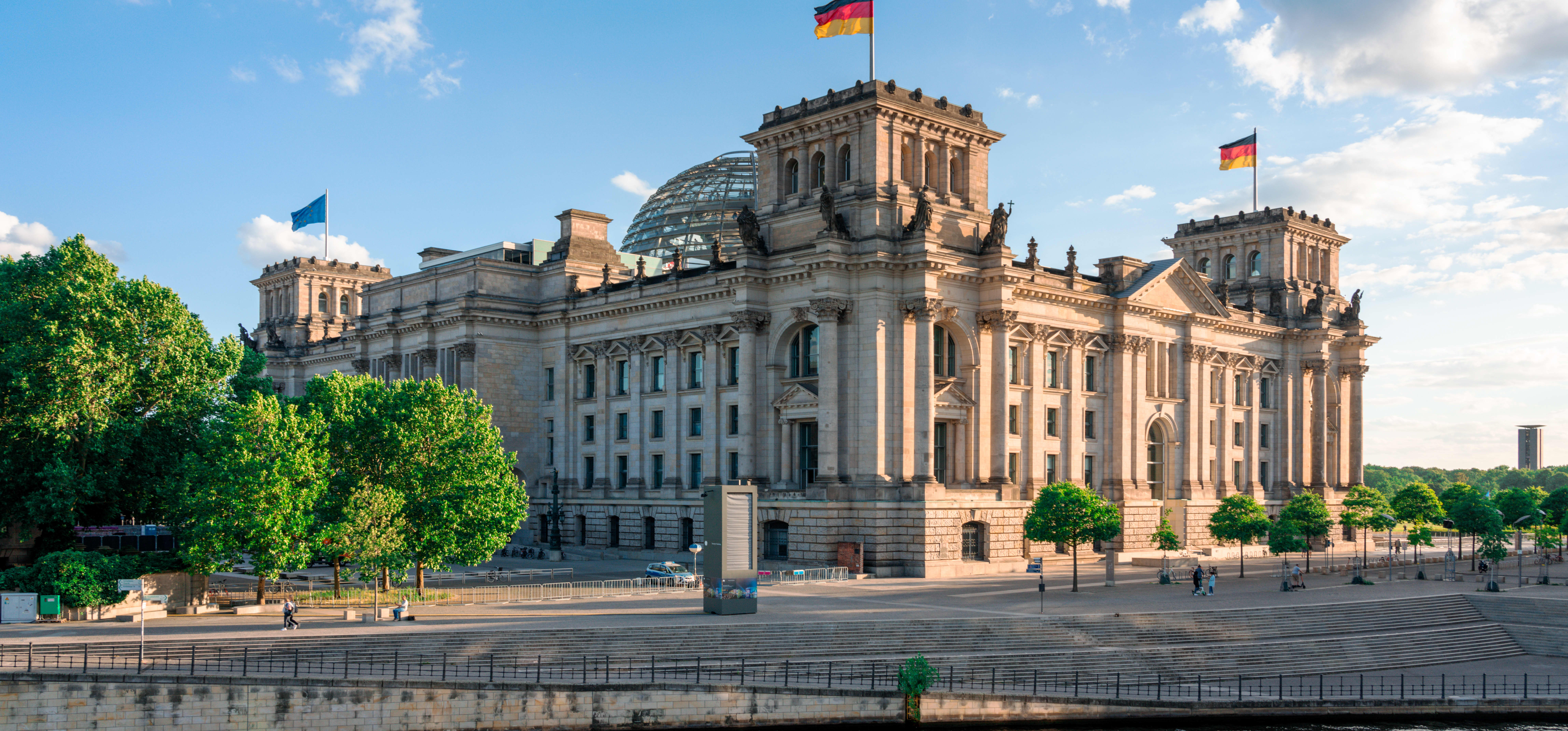 Seitenansicht des Reichstagsgebäudes in Berlin mit blauem, leicht bewölktem Himmel und Sonnenschein