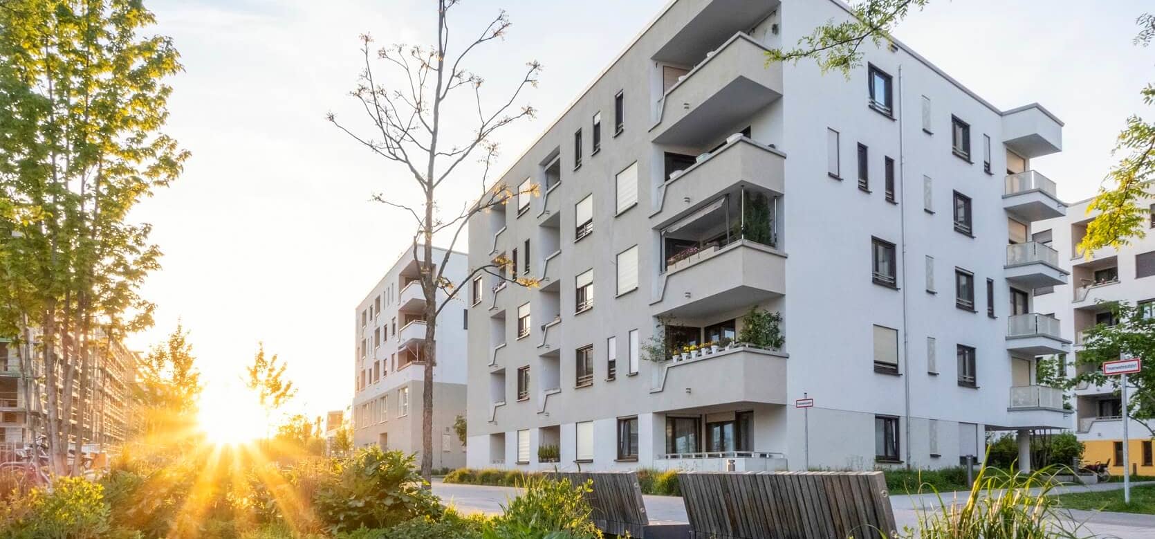 Grünanlage vor einem modernen Mehrfamilienhaus in Deutschland bei Sonnenuntergang