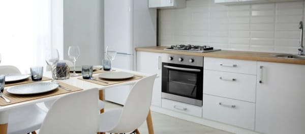 weiße Einbauküche mit gedecktem Esstisch