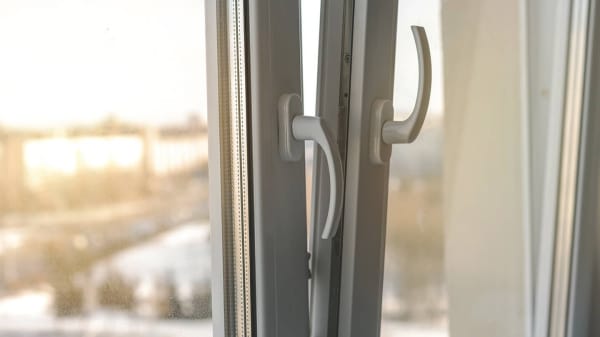 Geöffnetes Kunststoff-Fenster mit weißen Griffen bei Tageslicht