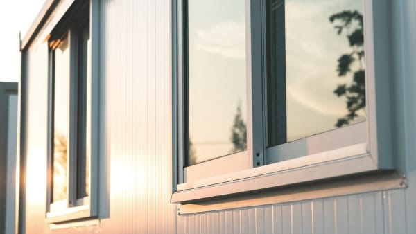 Moderne weiße Fensterfassade bei Sonnenuntergang – reflektierende Scheiben und Rahmen
