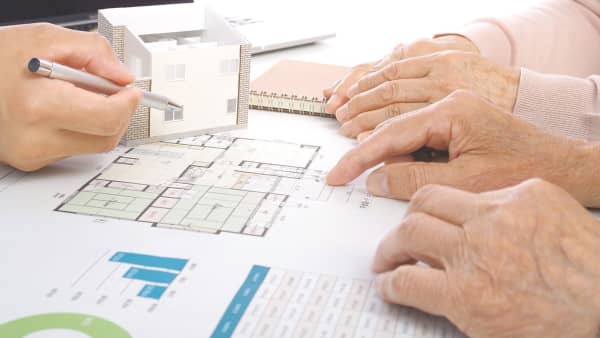 Hände älterer Personen zeigen auf einen Plan zum altersgerechten Umbau