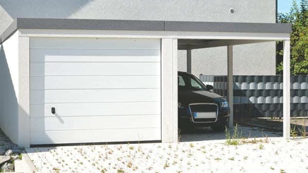 Weiße Fertiggarage mit einem Carport daneben gebaut