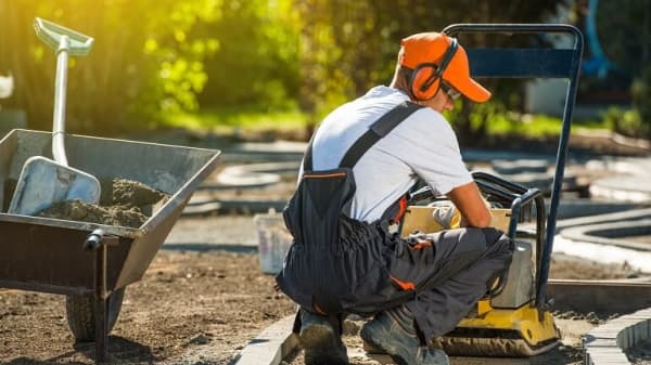 Handwerker bereitet Pflasterung eines Gartenwegs vor.