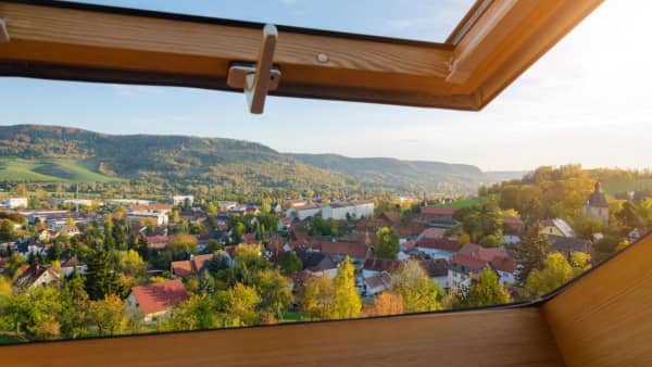 Dachfenster mit Holzrahmen mit Ausblick über die Stadt