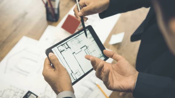 Immobiliengutachter schaut sich Grundrisse auf dem Tablet an