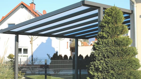 Carport aus Metall mit transparentem Dach neben Wohnhaus