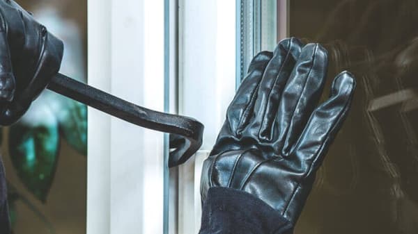 Einbruch mit Brecheisen an Fenster – Nahaufnahme mit Handschuhen