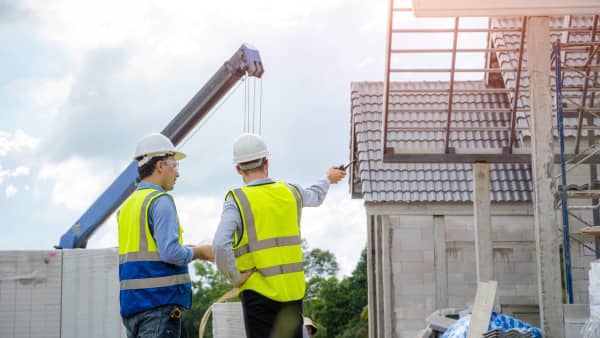 Bauleute vor dem unfertigen Neubau eines Wohngebäudes