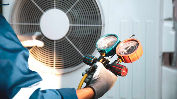Mechaniker überprüft Kältemittel in einer Wärmepumpe mit einem Manometer