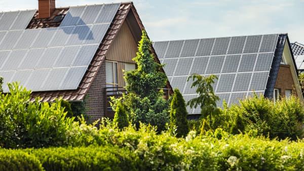 Zwei Wohnhäuser mit Solaranlagen auf den Dächern im Grünen