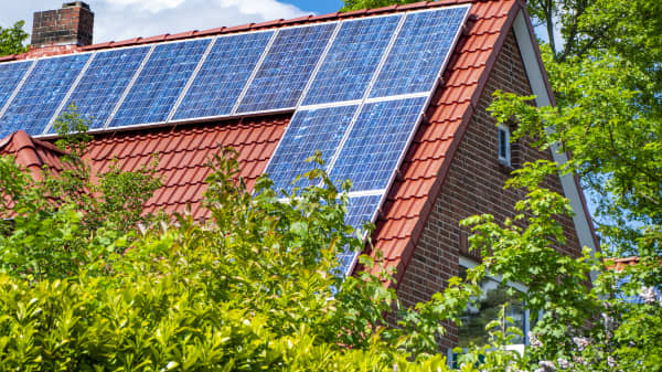 Sonnenkollektoren auf einem roten Giebeldach bei Sonnenschein