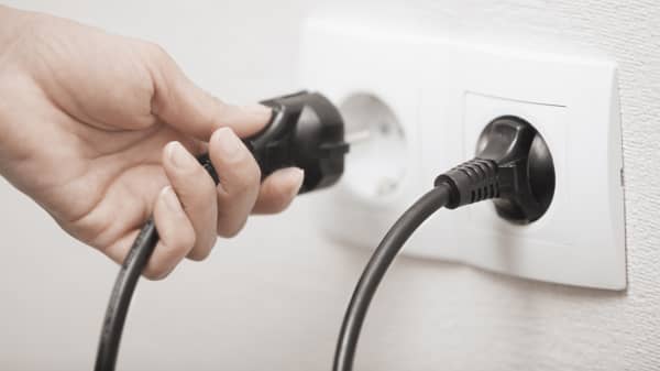 Frau steckt einen Stecker in eine Steckdose, Nahaufnahme ihrer Hand